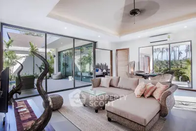 Luxurious living room with modern decor and garden view, featuring elegant wicker furniture and large glass doors.