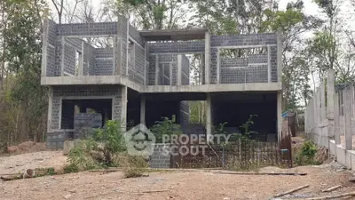 Under-construction modern concrete house with open framework in a wooded area, showcasing potential for customization.