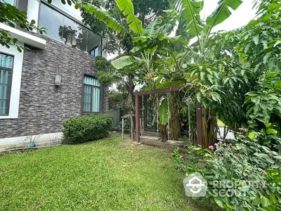 Charming garden view with lush greenery and modern stone facade in a serene residential setting.