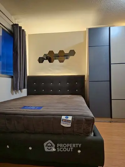 Modern bedroom with stylish bed and mirrored wall decor, featuring sleek wardrobe design.