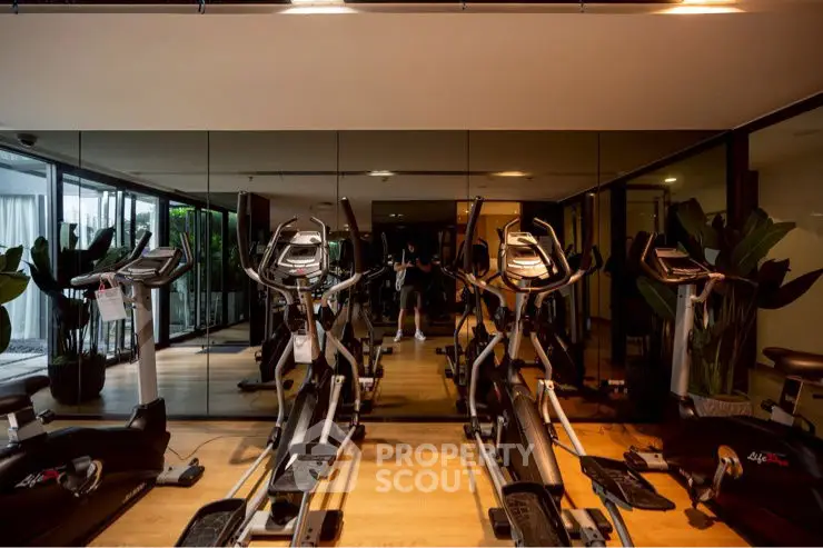 Modern gym with exercise equipment and mirrored walls in luxury apartment building.