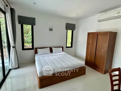 Spacious bedroom with large windows and modern furnishings, perfect for a serene living experience.