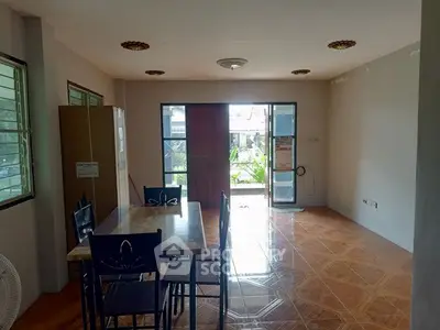 Spacious dining area with natural light and garden view, featuring a wooden table and chairs.