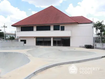 Modern building with red roof and skate park in front, perfect for urban lifestyle enthusiasts.