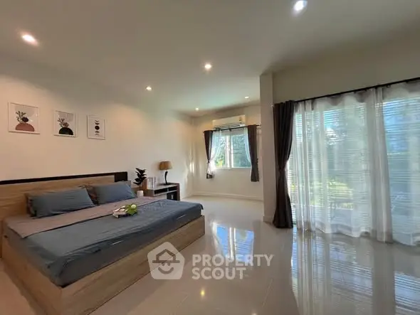 Spacious bedroom with large windows and modern decor, offering a serene and inviting atmosphere.