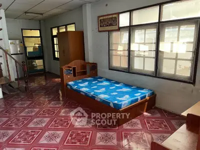 Spacious room with single bed and large windows, featuring unique red patterned flooring.