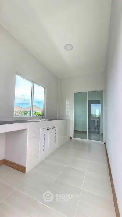 Spacious kitchen with modern design and ample natural light, featuring sleek countertops and large windows.
