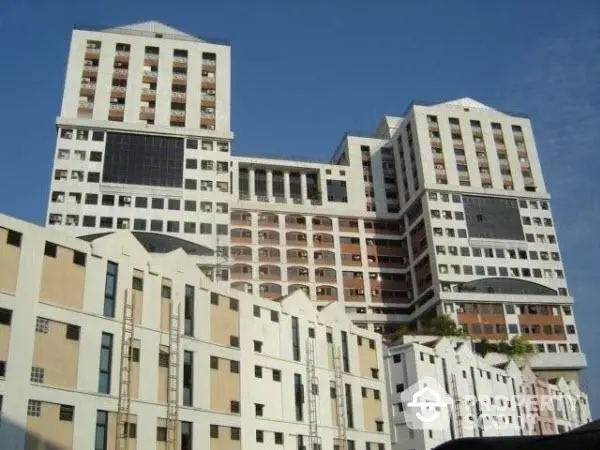 Modern multi-story residential complex with a mix of architectural designs, showcasing a variety of balconies and windows under a clear blue sky.