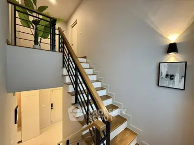 Modern staircase with wooden steps and sleek railing in a stylish home interior.