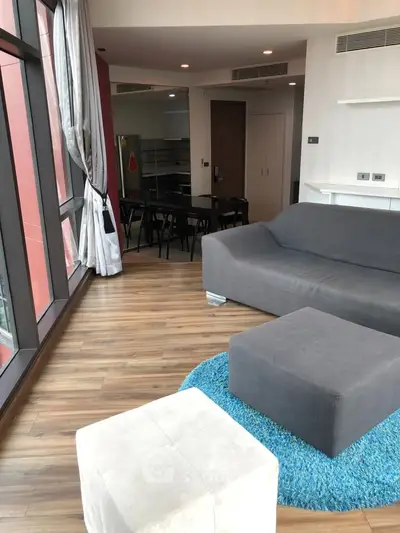 Spacious modern living room with large windows and stylish furniture in a high-rise apartment.