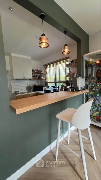 Modern kitchen with open layout and stylish lighting, featuring a breakfast bar and contemporary decor.
