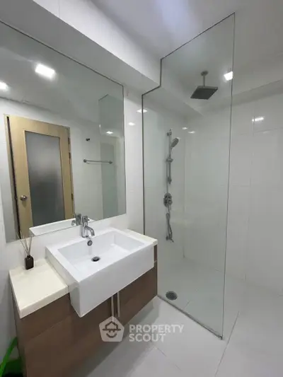 Modern bathroom with glass shower and sleek vanity in minimalist design.
