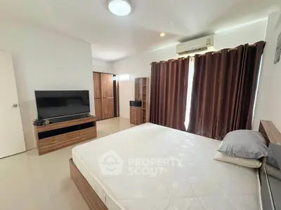 Spacious bedroom with modern furnishings and natural light, featuring a large bed and entertainment unit.