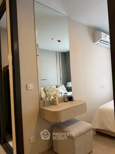 Modern bedroom with stylish vanity and mirror, featuring neutral tones and elegant decor.