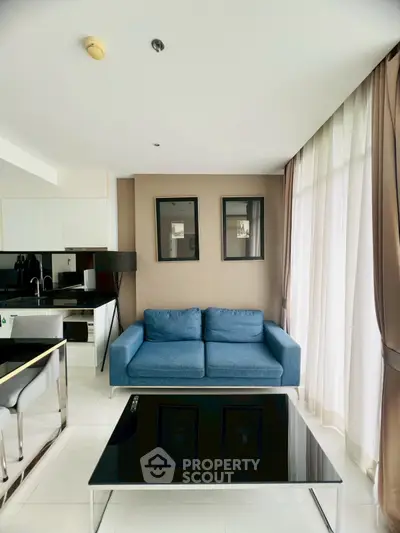 Modern living room with blue sofa and sleek kitchen in open layout apartment.