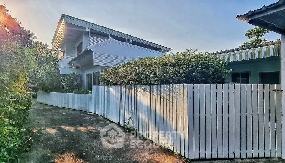 Charming modern house with lush greenery and white picket fence