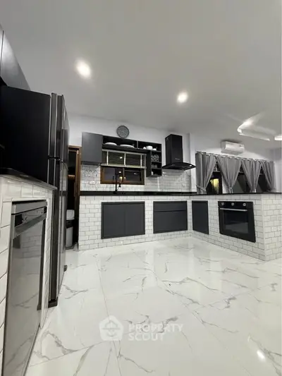 Modern kitchen with sleek black cabinets, white subway tiles, and marble flooring, featuring an open layout and built-in oven.