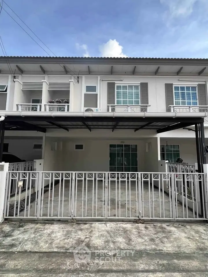 Modern townhouse exterior with gated parking and balcony, ideal for urban living.