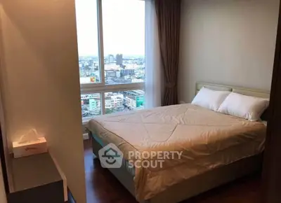Cozy bedroom with city view, featuring a comfortable bed and large window for natural light.