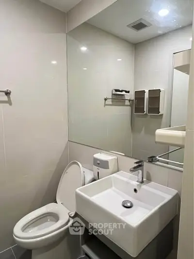 Modern bathroom with sleek fixtures and large mirror in a contemporary apartment.