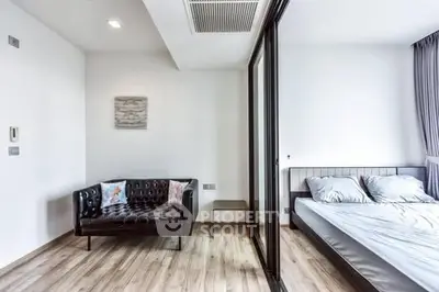 Modern bedroom with glass partition and stylish sofa in a bright apartment.