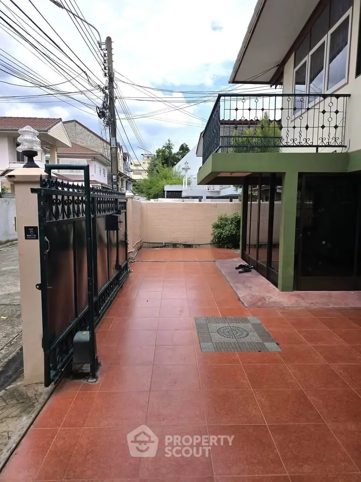 Charming residential entrance with tiled pathway and elegant wrought iron gate.