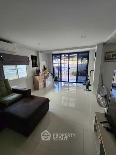 Spacious living room with modern decor and large windows opening to a balcony.