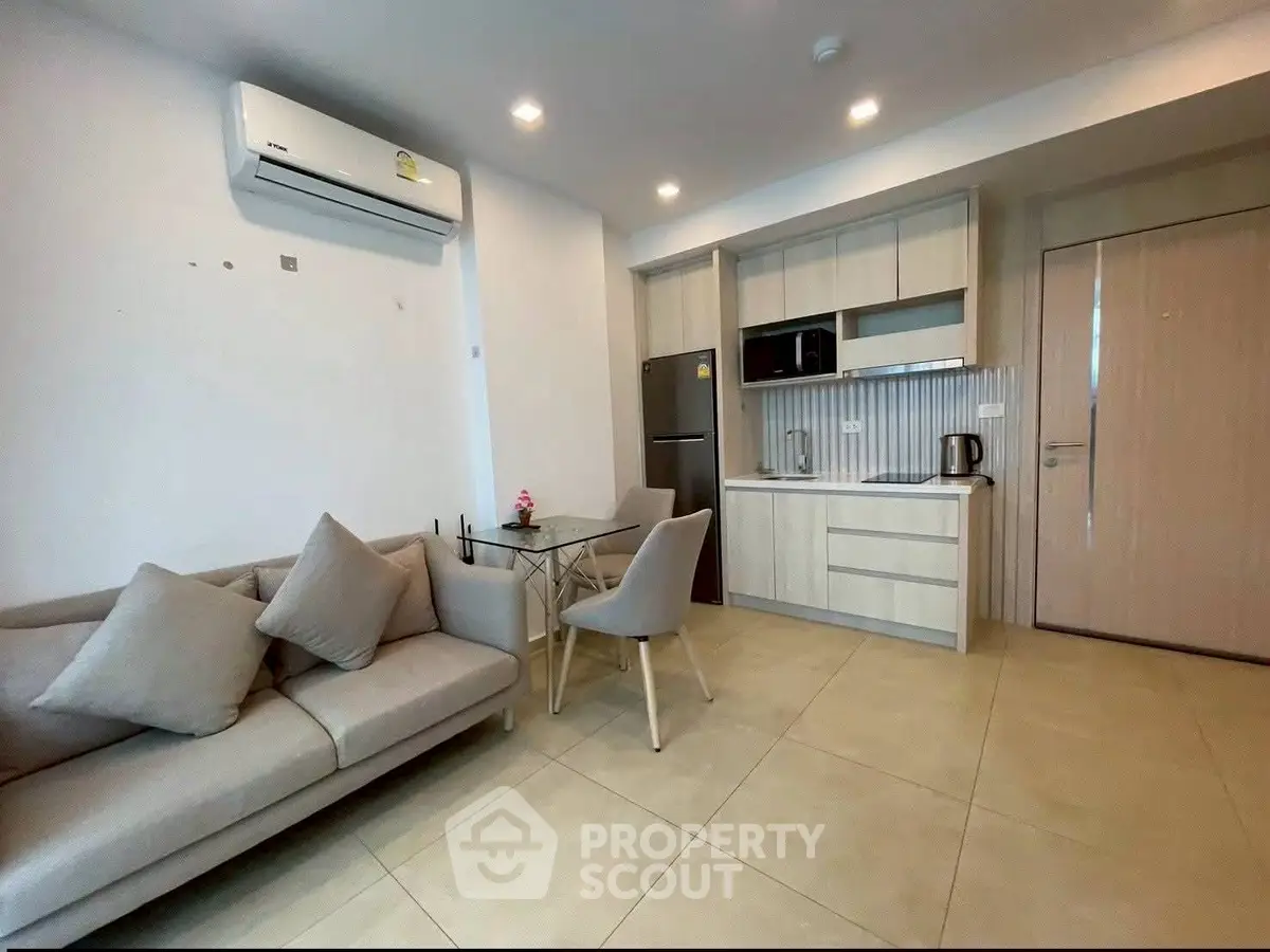 Modern open-layout living room with kitchen, featuring sleek furniture and appliances.