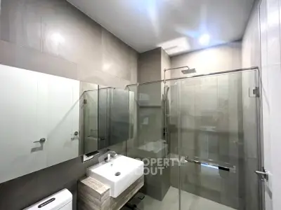 Modern bathroom with glass shower and sleek fixtures in contemporary apartment.