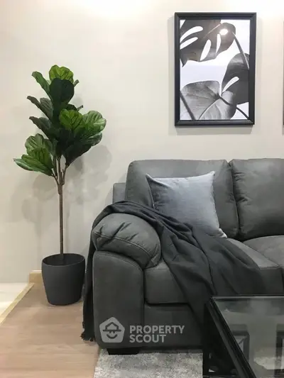 Stylish living room with modern gray sofa, elegant decor, and lush indoor plant for a cozy ambiance.