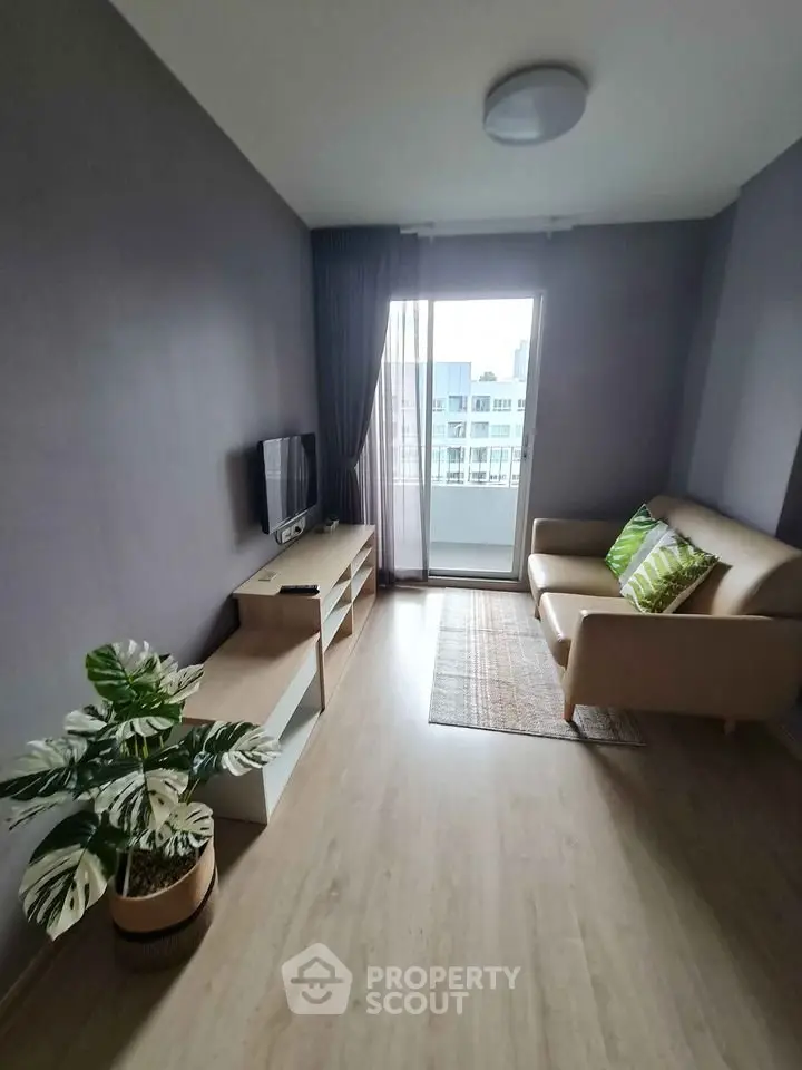 Modern living room with cozy sofa and TV, featuring a large window with city view.