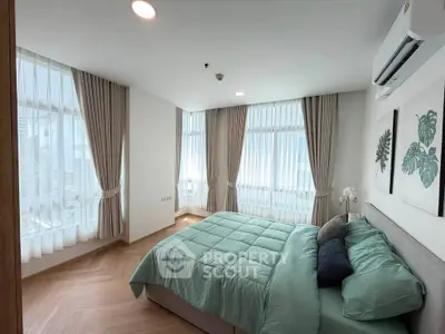 Spacious bedroom with large windows and modern decor in a high-rise apartment.