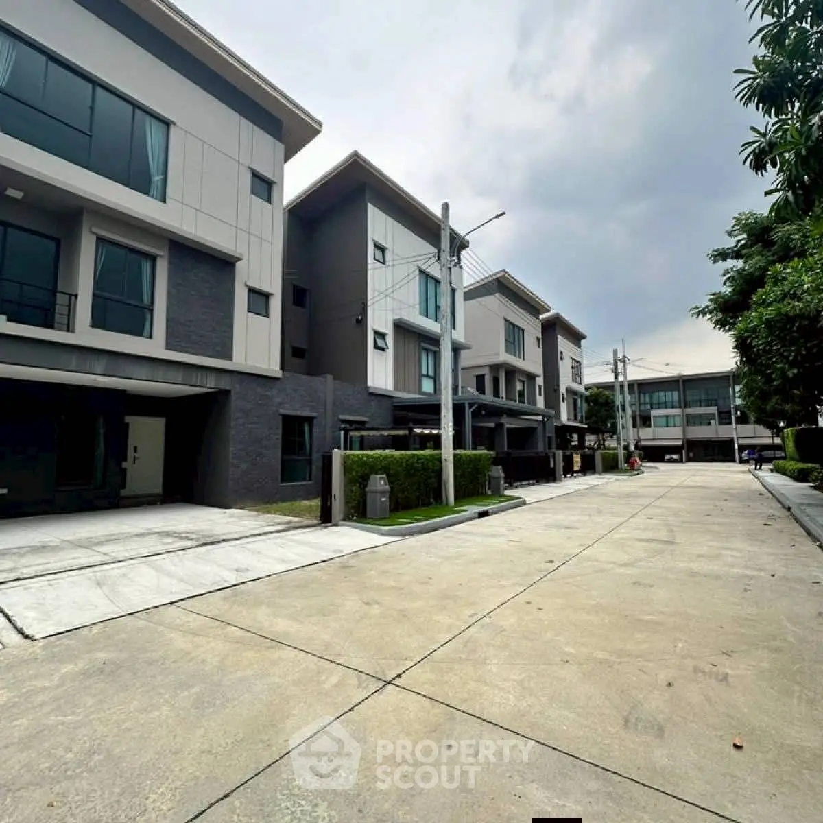 Modern townhouse complex with spacious driveways and lush greenery.