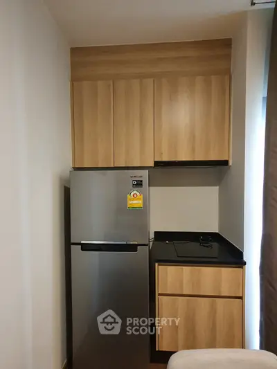 Compact kitchen with modern fridge and wooden cabinets