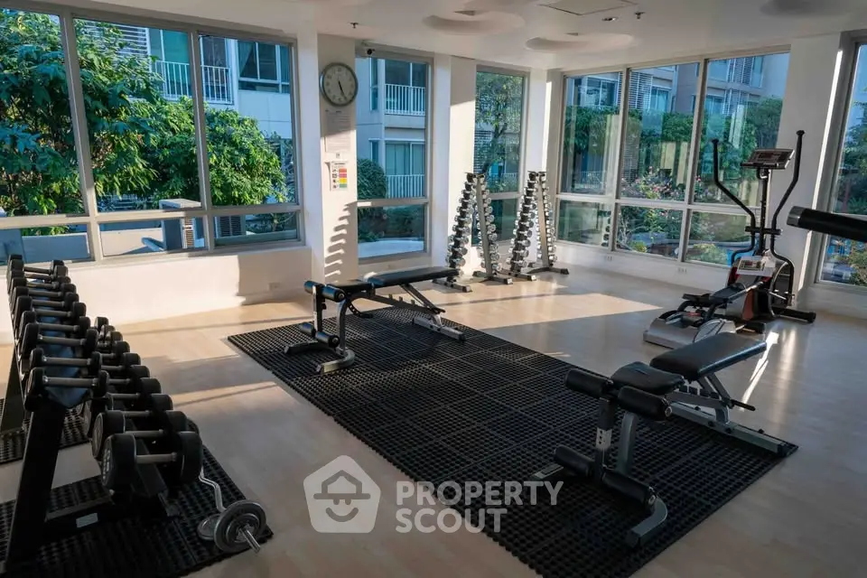 Modern gym with large windows and fitness equipment in a residential building.