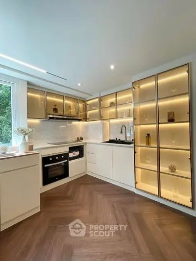 Modern kitchen with sleek cabinetry and built-in appliances, featuring elegant lighting and a stylish open layout.