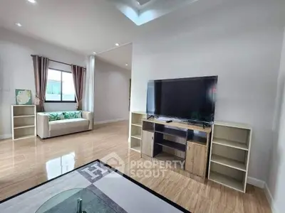 Spacious living room with modern TV setup and cozy seating area.