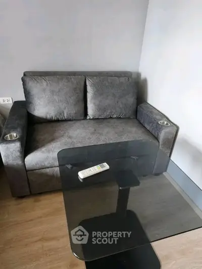 Modern living room with stylish gray sofa and sleek glass coffee table, perfect for cozy relaxation.