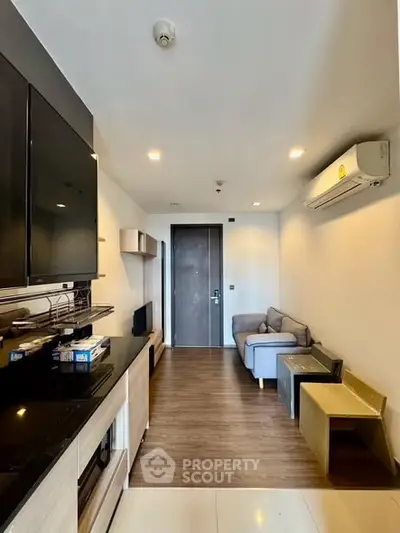 Modern living room with sleek design, featuring a cozy sofa, wall-mounted TV, and air conditioning.