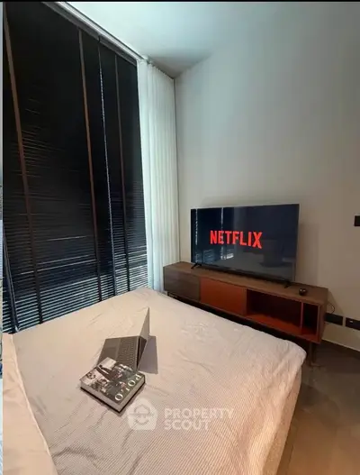 Cozy bedroom with modern decor, featuring a TV and laptop, perfect for relaxation and entertainment.