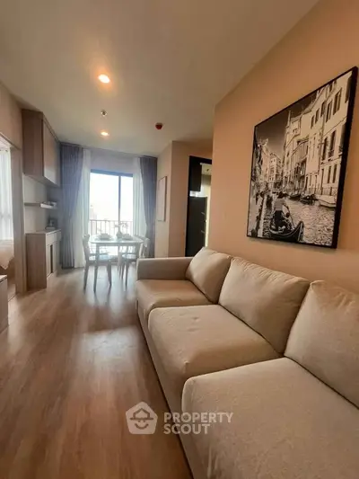 Spacious modern living room with large sofa and dining area, featuring elegant decor and natural light.