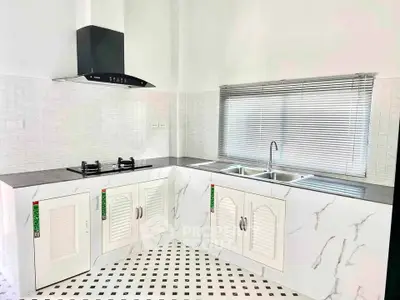 Modern kitchen with sleek marble countertops and gas stove in a bright, airy space.