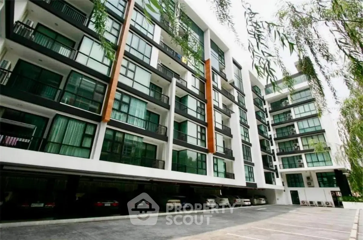 Modern apartment building with spacious balconies and ample parking space.
