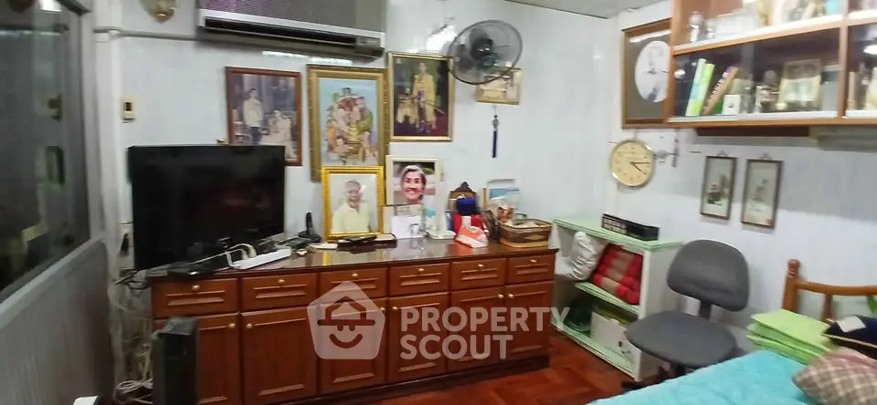 Cozy living room with vintage decor and wooden furniture, featuring a TV and air conditioning unit.
