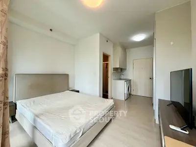 Modern studio apartment with bed, kitchenette, and washing machine, ideal for urban living.