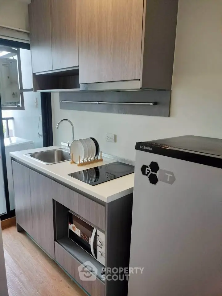 Modern compact kitchen with sleek cabinetry and appliances in a stylish apartment.