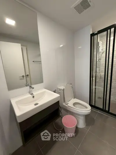 Modern bathroom with sleek design, featuring a glass shower and contemporary fixtures.