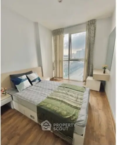 Bright and cozy bedroom with large window and modern decor in urban apartment.