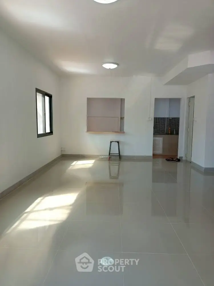 Spacious unfurnished living room with glossy tiled floors and natural light.
