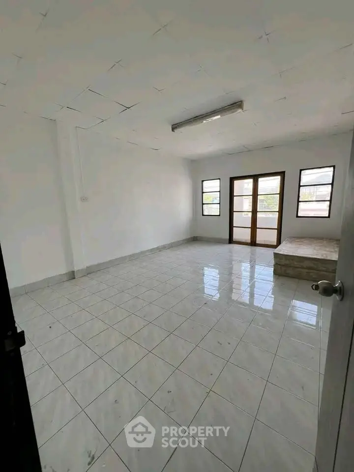 Spacious empty room with tiled flooring and large windows for natural light.